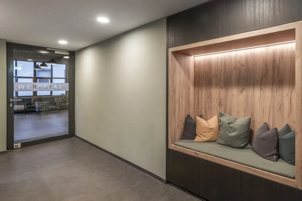 gemuetliche Sitznische aus Holz mit gruenen und gelben Kissen