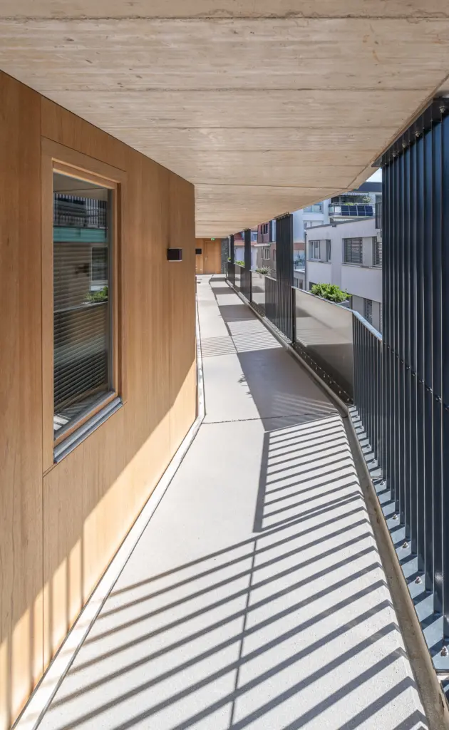 laubengang zu den Zimmern in 3. Stock mit Betondecke und Holzfassade