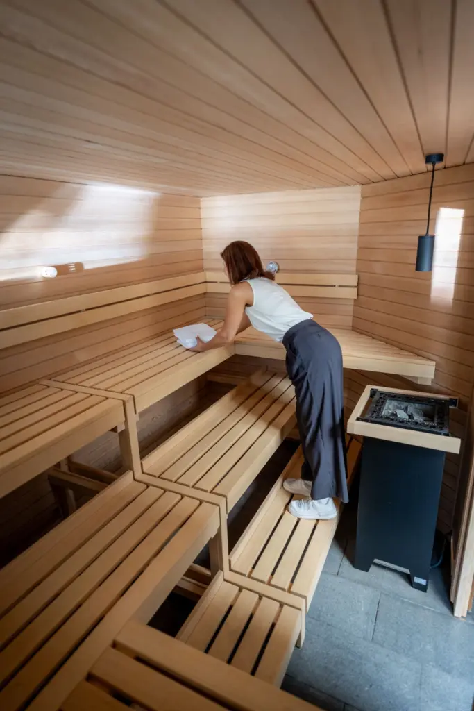 großzuegige Sauna, eine Person platziert ein zusammengelegtes Handtuch