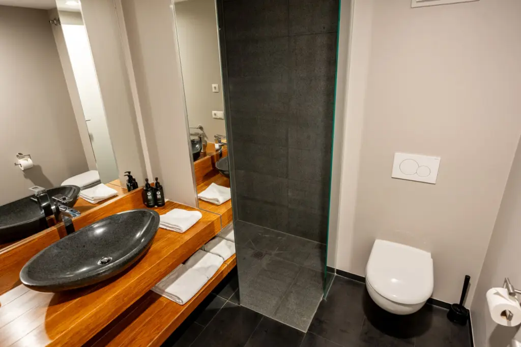 Badezimmer im Stammhaus mit Holzwaschtisch, Granitwaschbecken und ebenerdiger Dusche