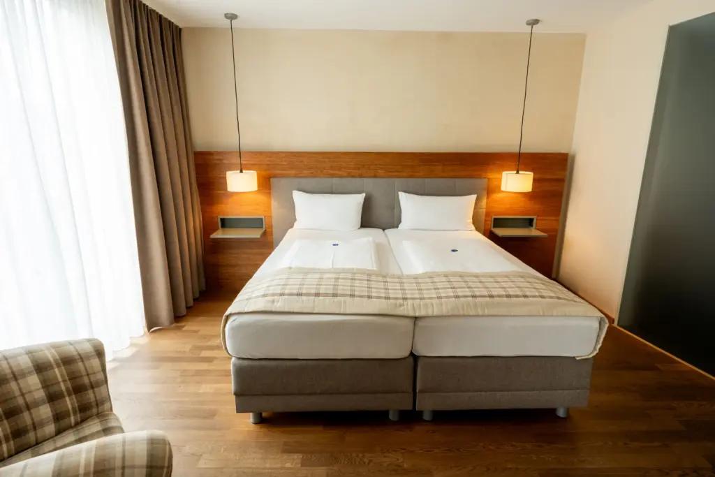 mit warmen Hoelzern eingerichtetes, gemuetliches Hotelzimmer mit Boxspringbett