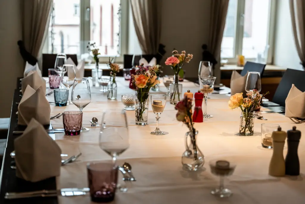 große eingedeckte Blocktafel mit frischen Blumen und Kerzen
